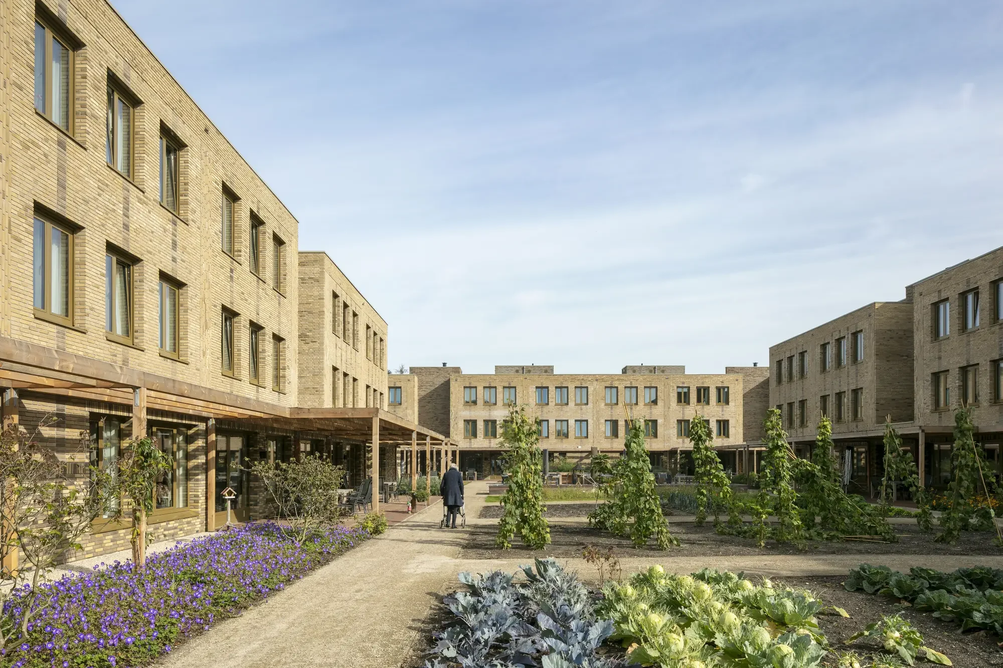 The story of a caring community - woman walking through the gardens of a care-home